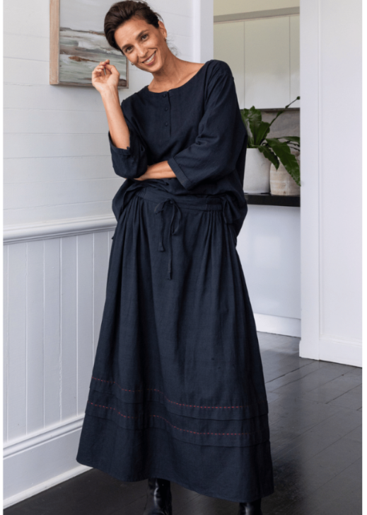 Woman wearing a black dress in a room with white walls and a plant.